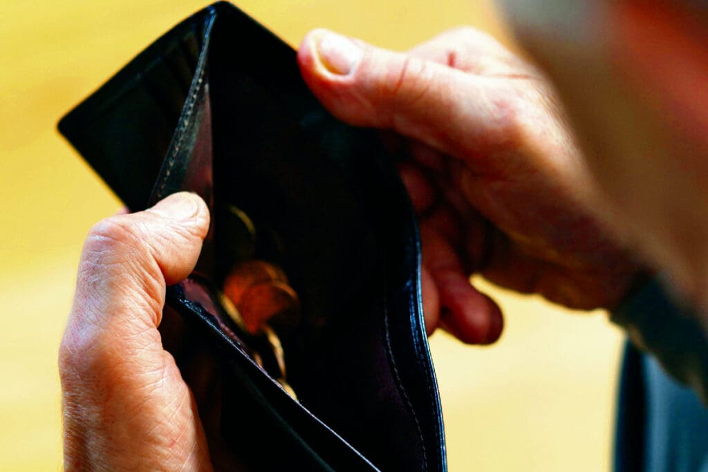 Close up of poor senior man holding empty wallet